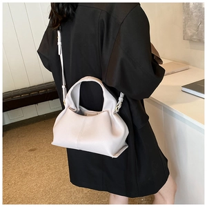Borsa a nuvola moderna in morbida pelle chiara indossata da modella in abito nero