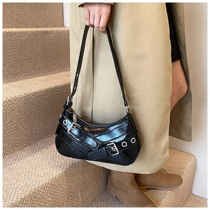Sac sous le bras tendance en similicuir noir avec boucles argentées porté avec un trench