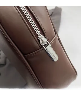 Détail d'une fermeture éclair en métal argenté sur un sac à main en cuir marron foncé