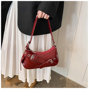 Détail du sac à bandoulière en similicuir bordeaux avec boucles punk et œillets