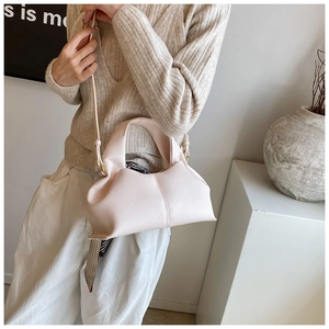 Detail of light apricot handbag featuring ruched handle and polka dot silk scarf decoration