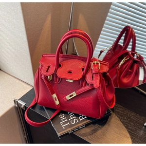 Detail of red lychee grain leather handbag with gold hardware and classic flip lock