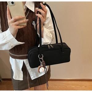 Detail der schwarzen Nylon-Schultertasche mit Baseball-Anhänger und doppelten Riemen