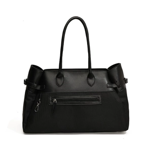 Minimalist black tote bag with textured nylon and leather patchwork for daily commute