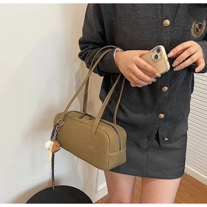 Detail of olive green Boston bag with vintage baseball glove and bat charms on shoulder strap