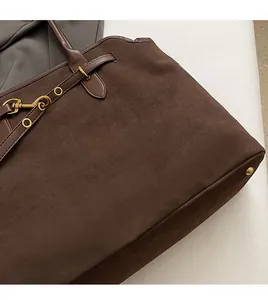 Detail of dark brown suede tote bag with vintage gold metal buckle and leather strap