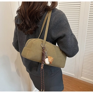 Close-up of olive green matte shoulder bag with baseball and glove pendant decoration