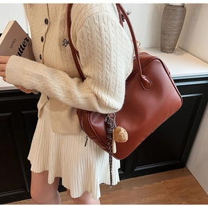 Détail latéral d'un sac cabas en cuir PU marron avec pendentif chapeau de paille