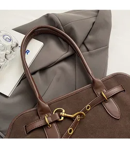 Detail of dark brown suede tote showing golden hardware and reinforced stitching on handle