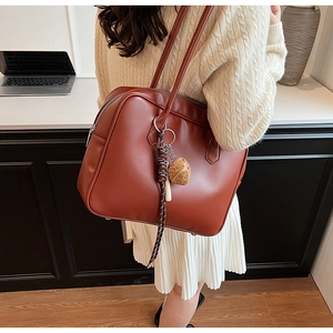 Détail d'un grand sac cabas en cuir PU caramel avec noeud tressé et pendentif coeur
