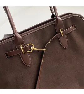 Close-up of golden hardware and premium matte suede texture on the brown tote bag