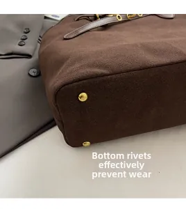 Close-up of golden metal rivets on the bottom of a brown suede tote bag for durability