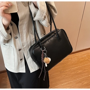 Gros plan sur le sac cabas en cuir noir mat avec un pendentif de baseball élégant
