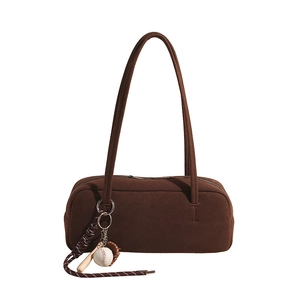 Brown suede underarm bag with baseball pendant and sleek rectangular retro design