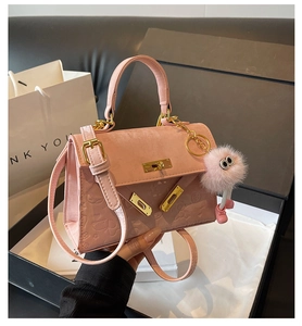 Detailed view of pink textured crossbody bag with animal embossing and furry charm