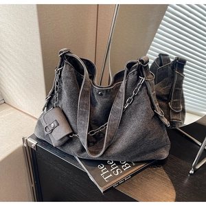 Détail d'un sac fourre-tout en jean gris foncé avec chaîne en métal et petit porte-monnaie