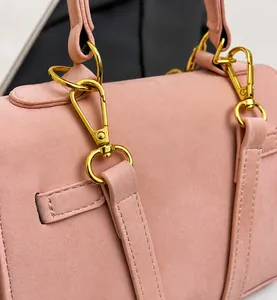 Detail of premium gold-toned lobster clasp and textured pink matte leather on handbag