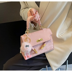 Pink embossed handbag with gold buckle and cute monster plush charm detail