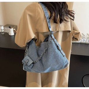 Detail of blue denim tote bag with silver chain worn by a model in a khaki coat