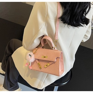 Detail of pink embossed leather bag with floral patterns and plush monster charm