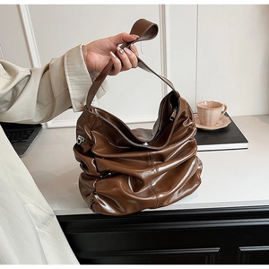 Dettaglio di una borsa a tracolla marrone lucida plissettata con cinturino largo elegante