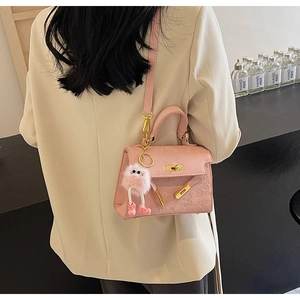 Close-up of pink embossed leather handbag with cute monster charm and gold lock