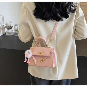Detailed view of pink mini handbag with cartoon embossing and fuzzy doll charm on model
