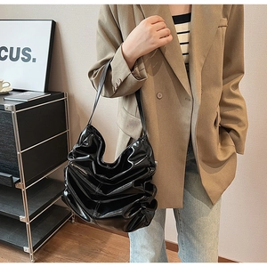 Dettaglio di una borsa tote in vernice nera con design a pieghe e finitura extra lucida
