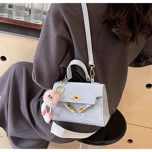 Detail of light blue crossbody bag with cartoon embossing and pink plush keychain