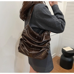 Vista laterale di una borsa hobo marrone scuro in pelle lucida con pieghe
