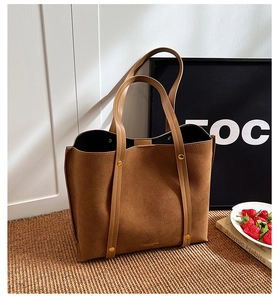 Detailed macro view of brown tote bag showing matte texture and gold rivet hardware