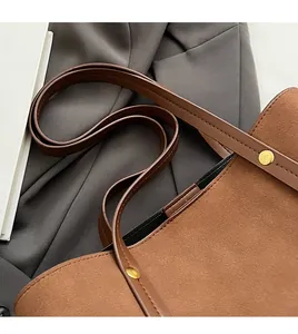 Close-up of brown suede tote bag with reinforced leather strap and golden rivets