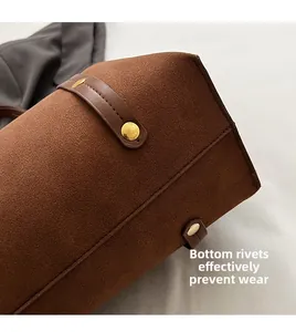 Macro detail of brown suede tote base with golden rivets for anti-wear protection