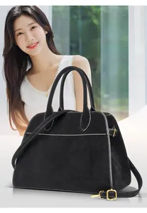 Detail of black matte suede tote bag featuring white contrast stitching and golden buckles