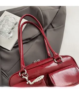 Détail du sac en cuir verni rouge brillant avec boucles argentées et breloque perle