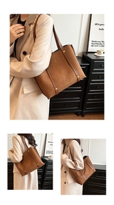 Close-up of vintage brown suede tote bag with leather straps and gold rivet accents