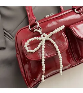 Détail d'un sac rouge en cuir verni avec doubles poches et nœud en perles