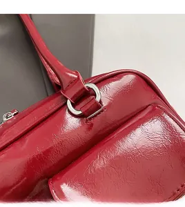 Détail du sac à bandoulière en cuir verni rouge montrant la texture et l'anneau en argent