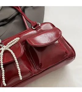 Détail d'un sac oreiller rouge brillant avec coutures fines et nœud en perles