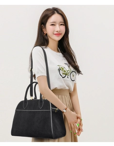 Detail of black suede tote bag with white contrast stitching and cylindrical handles