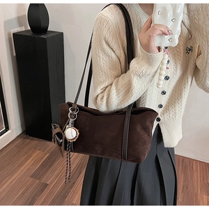 Detail of dark brown frosted tote bag with baseball charm on model wearing knit cardigan