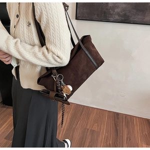 Detail of dark brown suede tote bag with adjustable strap and baseball themed pendants