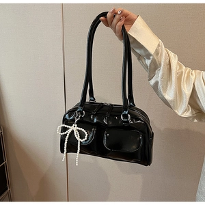 Detail of black patent leather bowling bag with twin pockets and pearl bow charm