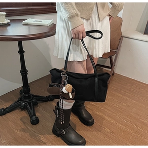 Detailed view of a black minimalist suede tote bag featuring a creative cookie charm