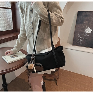 Close-up of black canvas tote bag with creative charms on a thin shoulder strap