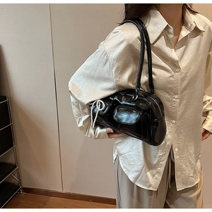 Détail d'un sac à bandoulière en cuir verni noir avec charm nœud en perles