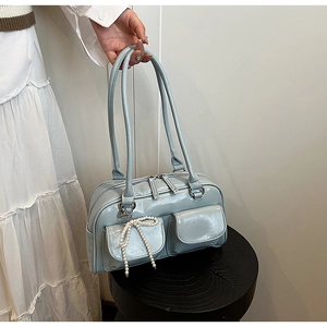 Détail du sac Boston bleu clair brillant avec poches avant et breloque en perles