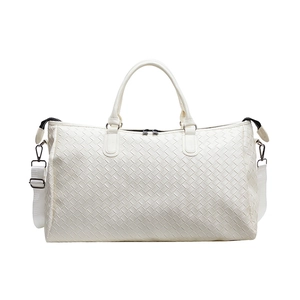 White woven travel duffle bag featuring top handles and detachable shoulder strap