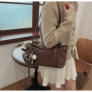 Deep brown suede shoulder bag featuring a baseball charm and spacious tote design