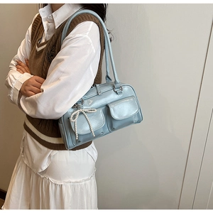 Détail du sac Boston bleu clair avec doubles poches et pendentif nœud en perles